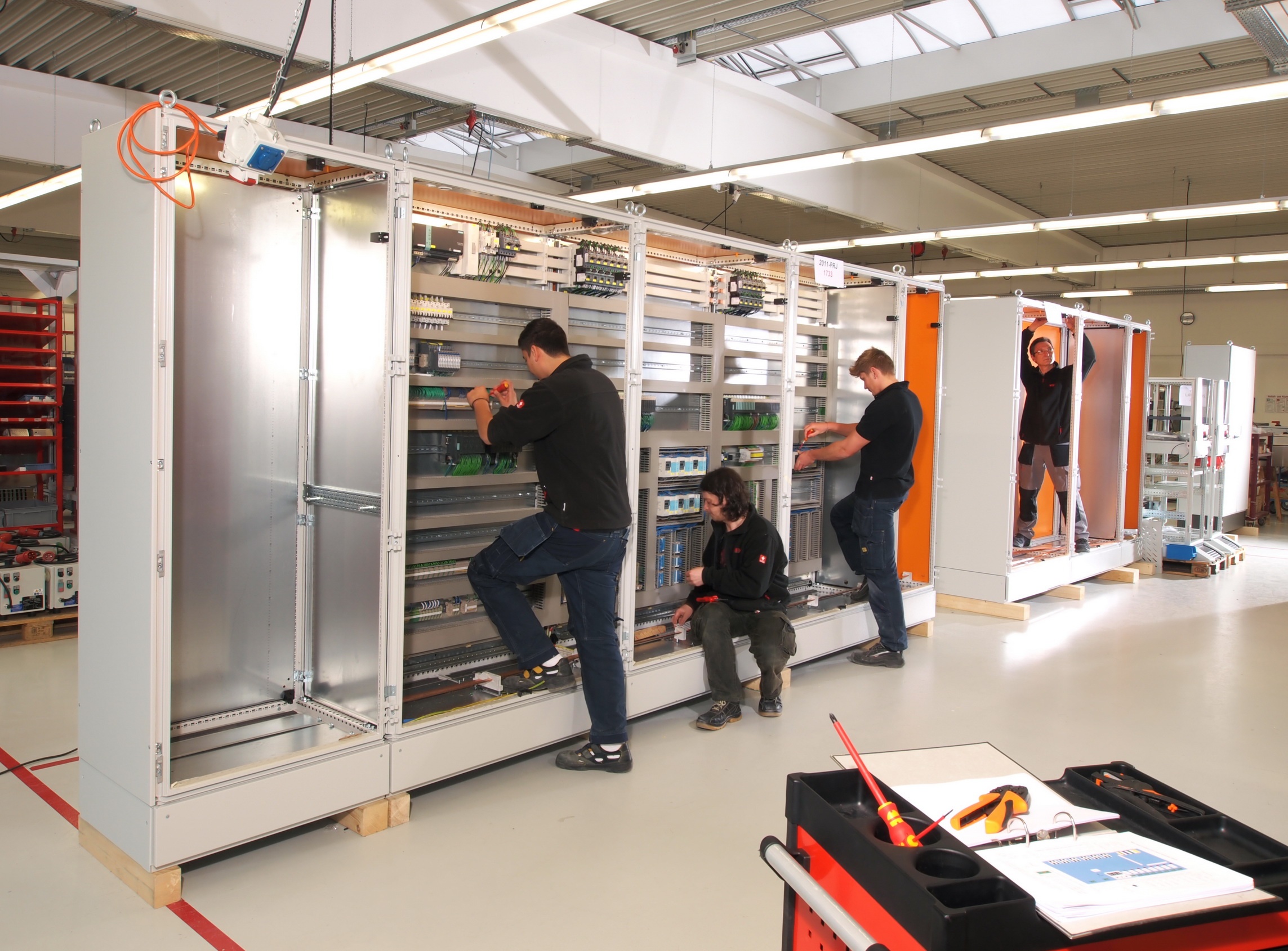 Wied Mitarbeiter arbeiten parallel an einer kompletten Schaltschrankreihe